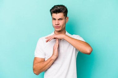 Mavi arka planda izole edilmiş genç beyaz bir adam bir mola hareketi gösteriyor..