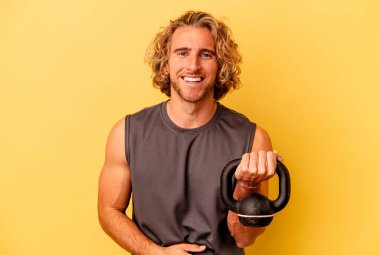 young sport man making weightlifting isolated on yellow background laughing and having fun.