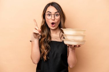 Beyaz tenli genç bir kadın bej arka planda saklanmış vaziyette. Bir fikri, ilham verici bir fikri var..