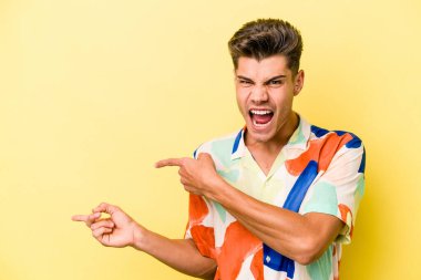 Sarı arka planda izole edilmiş genç beyaz adam işaret parmağıyla fotokopi alanını işaret ederek heyecan ve arzusunu ifade ediyor..