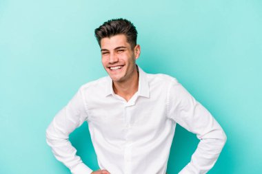 Mavi arka planda izole edilmiş genç beyaz adam mutlu, güler yüzlü ve neşeli.