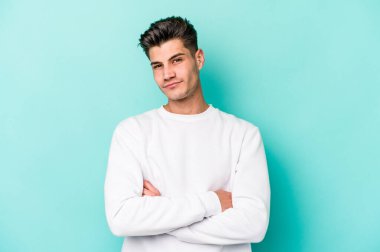 Kafkasyalı genç adam mavi arka planda izole edilmiş şüpheli, belirsiz, seni muayene ediyor..