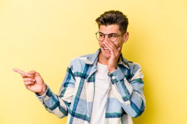 Sarı arka planda izole edilmiş genç beyaz bir adam bir dedikodu söylüyor, bir haber sunuyor..