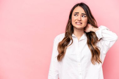 Kafkasyalı genç bir kadın pembe arka planda izole edilmiş kafasının arkasına dokunuyor, düşünüyor ve bir seçim yapıyor..