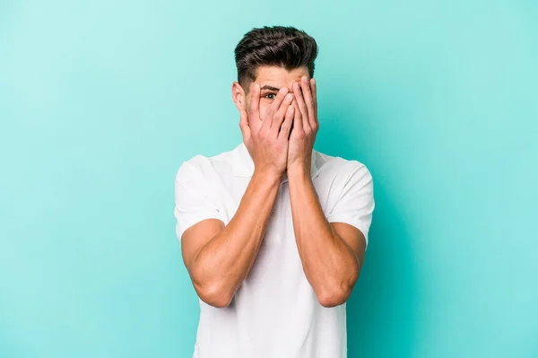 Ung Kaukasisk Man Isolerad Blå Bakgrund Blinka Genom Fingrarna Rädd — Stockfoto