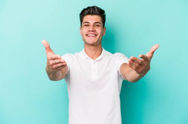 Mavi arka planda izole edilmiş beyaz bir genç hoş bir yüz ifadesi sergiliyor..