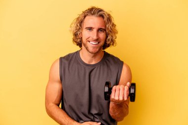 young sport man making weightlifting isolated on yellow background laughing and having fun.