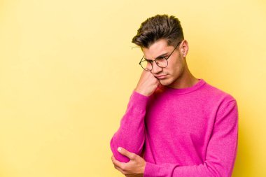 Sarı arka planda izole edilmiş genç, üzgün ve dalgın hisseden, kopyalama alanına bakan beyaz bir adam..