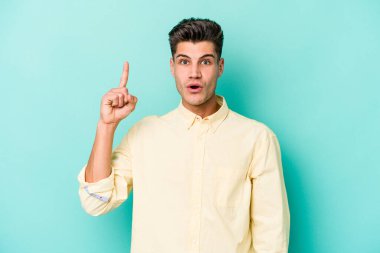 Mavi arka planda izole edilmiş beyaz bir adam ağzı açık bir şekilde üst tarafı işaret ediyor..