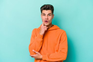 Kafkasyalı genç adam mavi arka planda izole edildi. Harika bir fikri var, yaratıcılık kavramı..