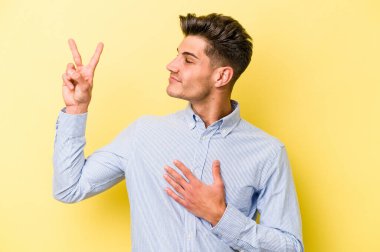 Sarı arka planda izole edilmiş genç beyaz adam yemin ediyor, elini göğsüne koyuyor..