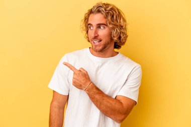 Sarı arka planda izole edilmiş genç beyaz adam gülümseyen, neşeli ve keyifli görünüyor..