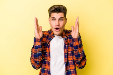 Sarı arka planda izole edilmiş genç beyaz adam şaşırdı ve şok oldu..