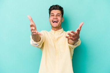 Mavi arka planda izole edilmiş genç beyaz adam kameraya sarıldığı için kendinden emin hissediyor..