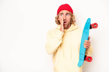 Young skater caucasian man isolated on white background is saying a secret hot braking news and looking aside