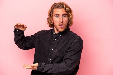 Pembe arka planda izole edilmiş beyaz bir adam iki eliyle bir şey tutuyor, ürün sunumu..