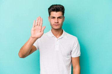 Mavi arka planda izole edilmiş genç beyaz adam elini uzatmış, dur işareti göstererek seni engelliyor..