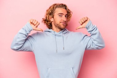 Pembe arka planda izole edilmiş genç beyaz adam gururlu ve kendinden emin hissediyor, örnek olarak.