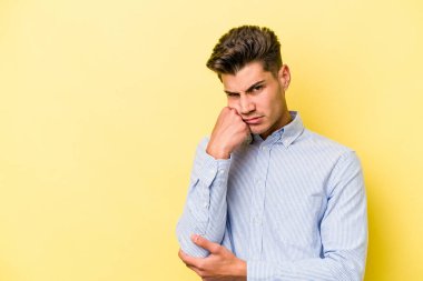 Sarı arka planda izole edilmiş genç, üzgün ve dalgın hisseden, kopyalama alanına bakan beyaz bir adam..
