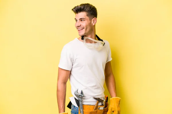 Young Electrician Caucasian Man Isolated Yellow Background Looks Aside Smiling — Stock Fotó