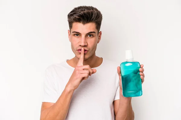 Young Caucasian Man Holding Mouthwash Isolated White Background Keeping Secret — Stock fotografie