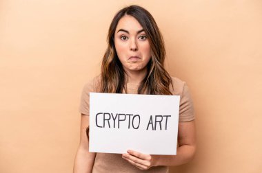 Kafkasyalı genç bir kadın elinde kripto bir pankart tutuyor. Arka planda izole edilmiş. Omuzlarını silkiyor ve gözleri açık..