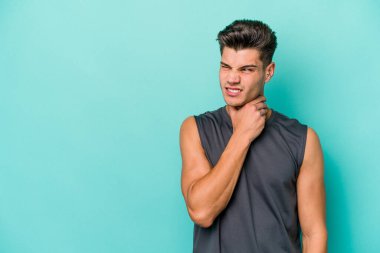 Kafkasyalı genç adam mavi arka planda izole edilmiş kafasının arkasına dokunuyor, düşünüyor ve bir seçim yapıyor..