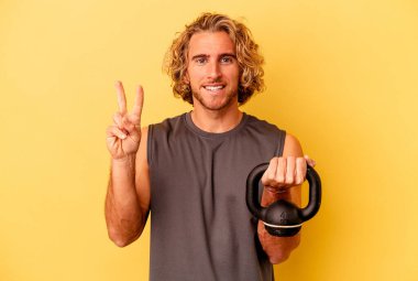 young sport man making weightlifting isolated on yellow background showing number two with fingers.