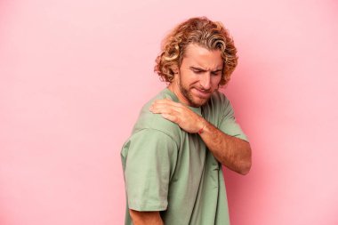 Pembe arka planda izole edilmiş, omuz ağrısı olan genç beyaz bir adam..