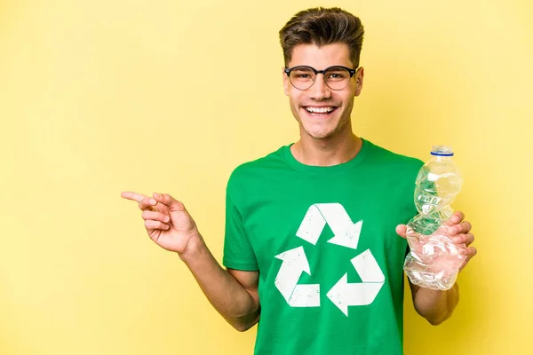 Mladý Běloch Drží Láhev Plastu Recyklaci Izolované Žlutém Pozadí Usmívá — Stock fotografie