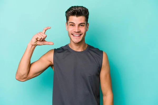 Joven Hombre Caucásico Aislado Sobre Fondo Azul Sosteniendo Algo Poco — Foto de Stock