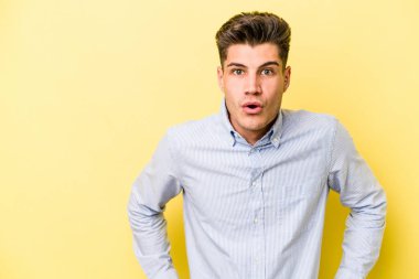 Sarı arka planda izole edilmiş genç beyaz adam gördüğü bir şey yüzünden şoka uğruyor..