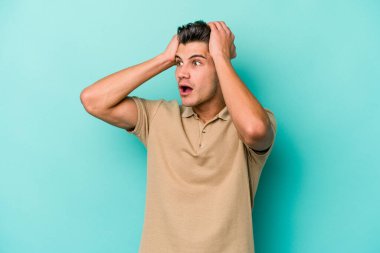 Genç beyaz adam mavi arka planda izole edilmiş bağırıyor, çok heyecanlı, tutkulu, bir şeyden memnun..