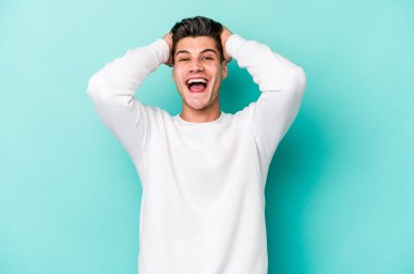 Genç beyaz adam mavi arka planda izole edilmiş bağırıyor, çok heyecanlı, tutkulu, bir şeyden memnun..