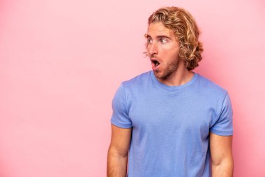 Pembe arka planda izole edilmiş genç beyaz adam gördüğü bir şey yüzünden şoka uğruyor..