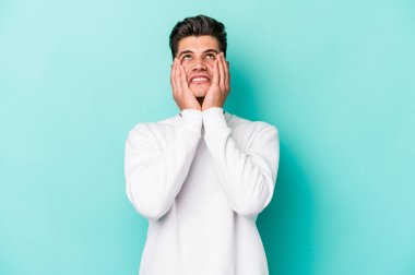 Kafkasyalı genç adam mavi arka planda izole edilmiş sızlanıyor ve ağlıyordu..