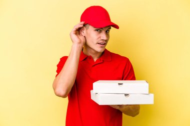 Sarı arka planda pizza tutan beyaz bir adam bir dedikoduyu dinlemeye çalışıyor..