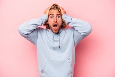 Pembe arka planda izole edilmiş genç beyaz adam şaşırdı ve şok oldu..
