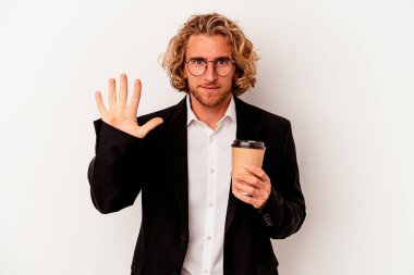Beyaz arka planda kahve tutan Kafkasyalı genç iş adamı gülümseyerek beş numarayı parmaklarıyla gösteriyor..