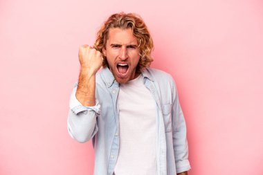 Pembe arka planda soyutlanmış, tasasız ve heyecanlı genç bir beyaz adam. Zafer konsepti.