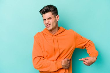 Mavi arka planda karaciğer ağrısı çeken, karnı ağrıyan genç beyaz bir adam..