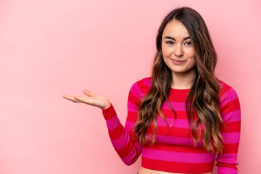 Pembe arka planda izole edilmiş genç beyaz kadın bir avuç içinde fotokopi alanı ve belinde bir el daha gösteriyor..