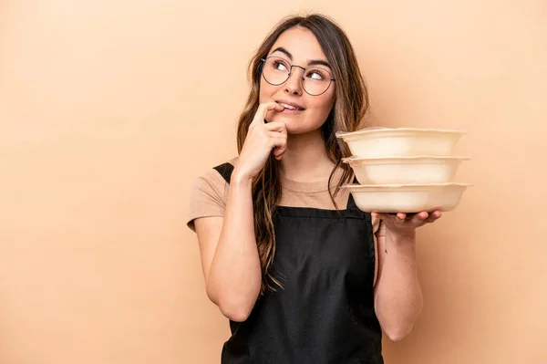 Ung Kaukasisk Kvinna Håller Tupperware Isolerad Beige Bakgrund Avslappnad Tänka — Stockfoto