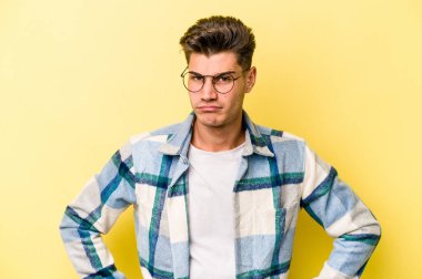 Kafkasyalı genç adam sarı arka planda izole edilmiş üzgün, ciddi yüzlü, mutsuz ve hoşnutsuz..