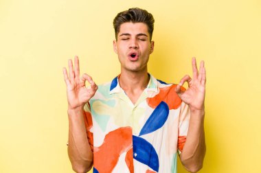 Sarı arka planda izole edilmiş genç beyaz adam sıkı çalışma gününden sonra rahatlıyor. Yoga yapıyor..