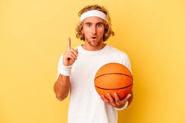 Genç basketbolcu beyaz adam sarı arka planda izole edilmiş. Harika bir fikri var, yaratıcılık kavramı..