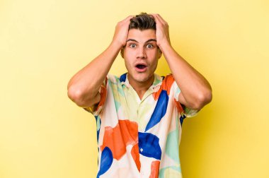 Sarı arka planda izole edilmiş genç beyaz adam şaşırdı ve şok oldu..