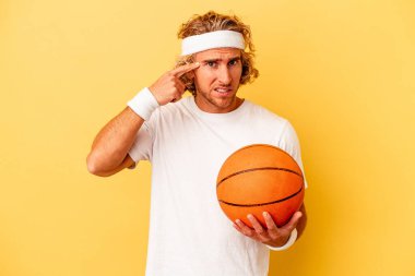Genç basketbolcu, sarı arka planda izole edilmiş beyaz adam işaret parmağıyla yaptığı hayal kırıklığı jestini gösteriyor..