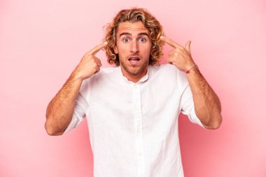 Pembe arka planda izole edilmiş genç beyaz adam işaret parmağıyla hayal kırıklığı jesti gösteriyor..