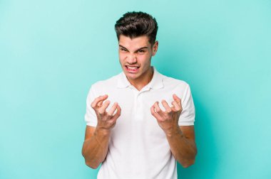 Mavi arka planda izole edilmiş genç beyaz adam gergin elleriyle çığlık atıyor..